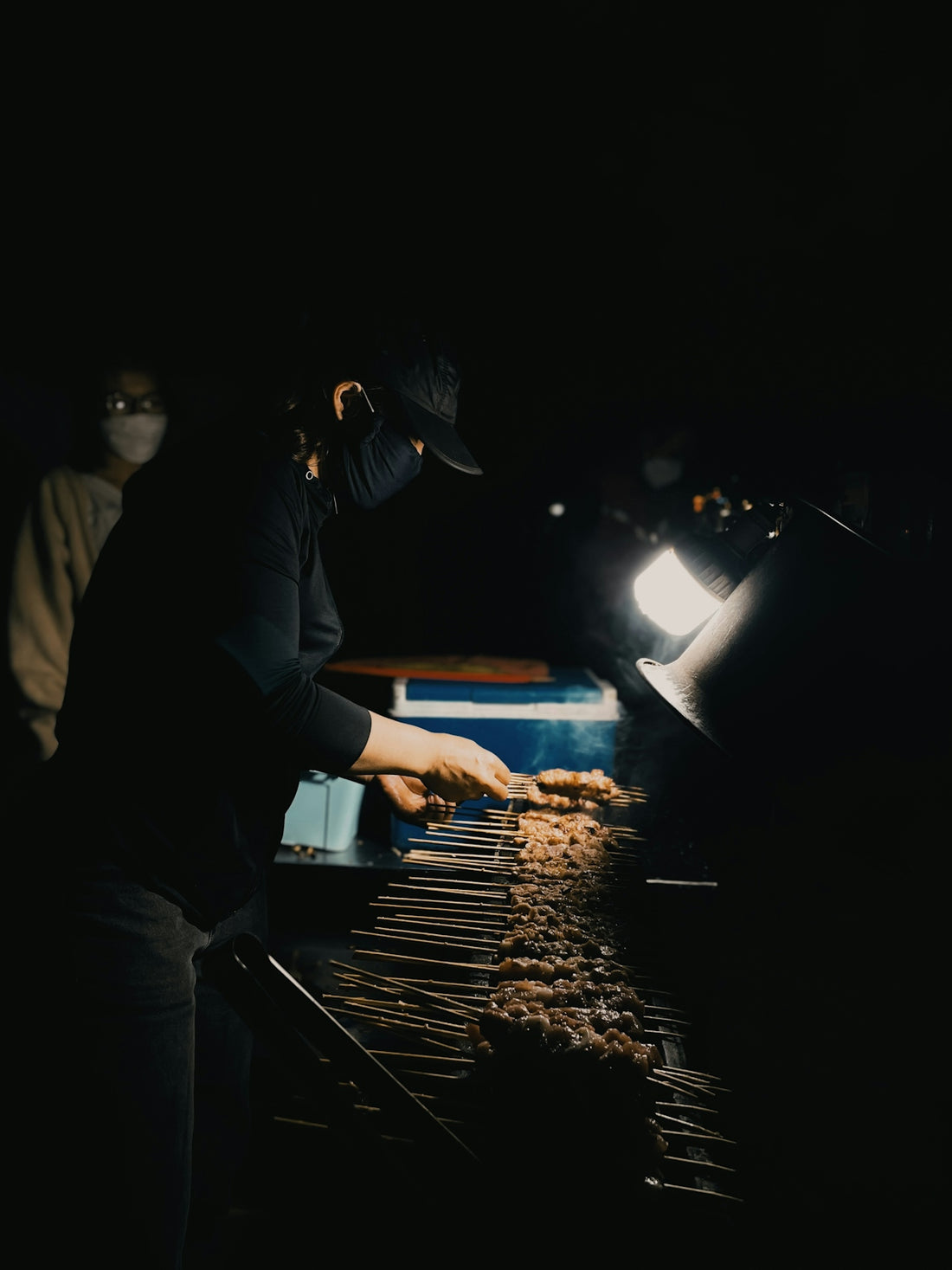 a person cooking food on a grill in the dark