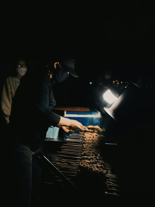 a person cooking food on a grill in the dark