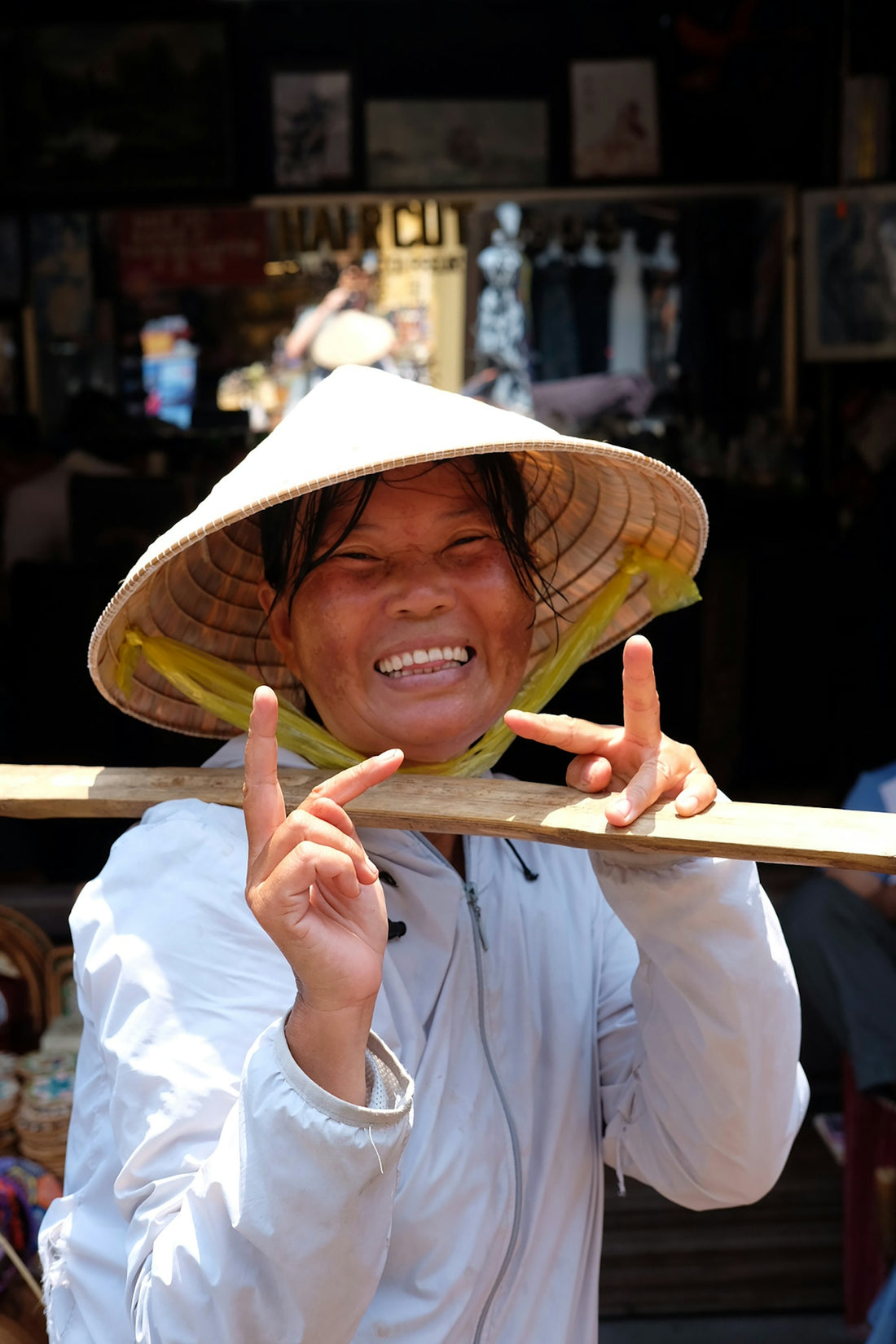 Smiling woman wearing a conical hat poses happily.