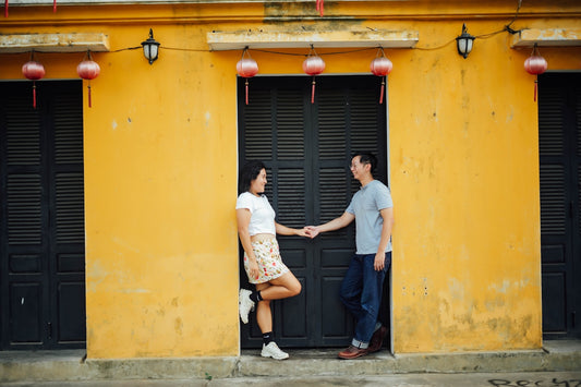 Couple holding hands in front of yellow building
