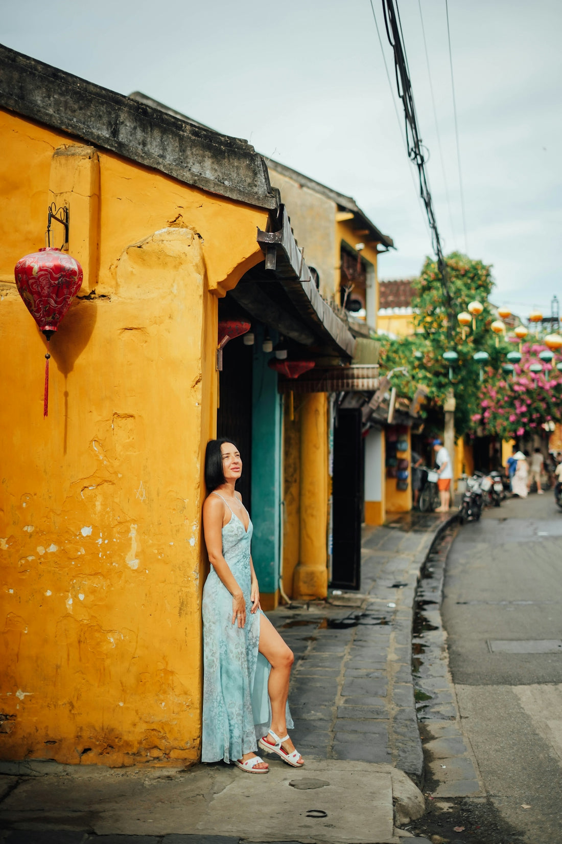 Woman leaning against a yellow wall on a street