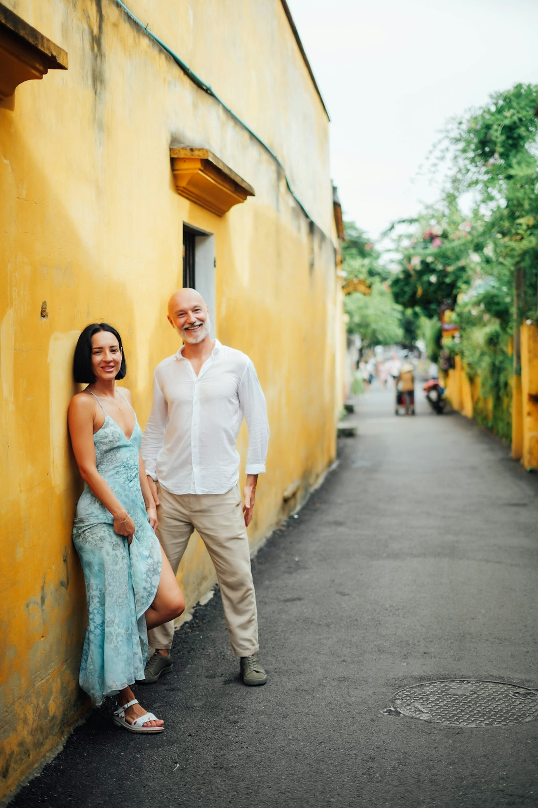 Couple posing against a yellow wall on a street