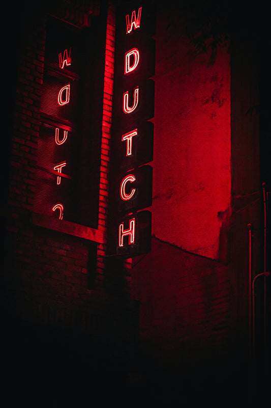 Red neon sign spelling out watch at night.