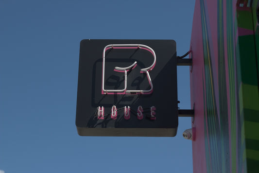 Neon sign for r house against blue sky